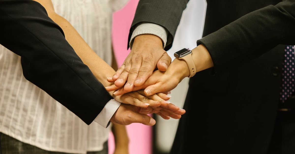 Close-up of colleagues huddling hands symbolizing teamwork and unity.